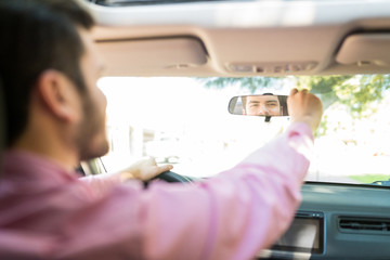 Man Checking Mirror With Reflection In Car