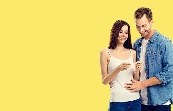 Love, relationship, new parents and happy family concept - young lovely couple, finding out results of a pregnancy test. Yellow background. Copy space for some text.