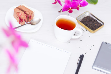 Cup of tea, flowers, spiral notepad, pen. Time management, new day planning concept.