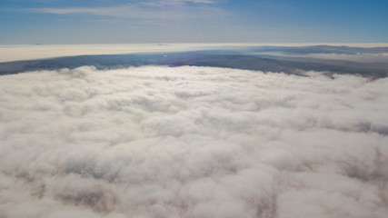 Landscape over the clouds in foggy weather. Hills of buildings in foggy weather. The drone and the top of the fog layer.