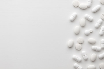 Scattered white pills on a white background. Bright monochrome composition. Pharmacology. Copy space