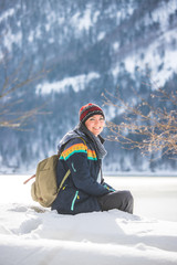 Fototapeta na wymiar Outdoor adventure: Caucasian girl is sitting in the snow and enjoying the view. Beautiful winter landscape, Austria