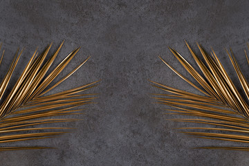 Closeup of golden palm leaves on abstract dark grey textured background. Tropical conceptual luxury...