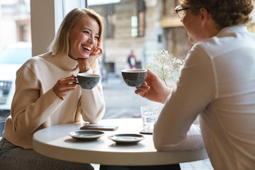 Couple sit in cafe indoors drinking coffee