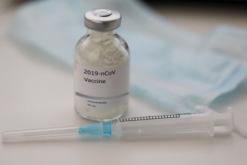 Vial with 2019-nCoV vaccine standing at table with empty syringe