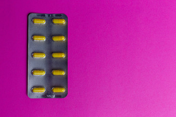 Silver pack of yellow capsules on pink background with copy space