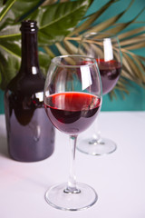 Two glasses with red grape wine with bottle on the background. Romantic dinner concept.