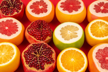 Grapefruit, orange, pomegranate, citrus sweetie on red background.
