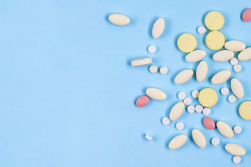 Assorted pharmaceutical medicine pills, tablets on blue background with copy space. Health care. Top view.