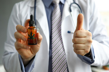 Male GP holding in hand cbd oil jar showing thumb up sign