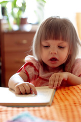 Little girl on a sunny day learns to read in bed.