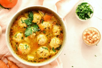 Soup with meatballs and vegetables on a white table background, top view. Vegetable soup with chicken and beans.