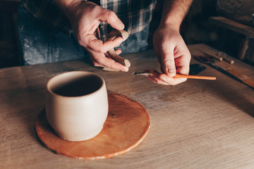 Obraz na płótnie Canvas Potter glues ears to a cup. Process of creating a ceramic cup
