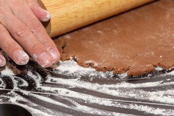 Rolling dough for gingerbread cookie. Rolling pin in male hands. Close-up.
