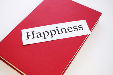 on the red book is a strip of paper with the word happiness