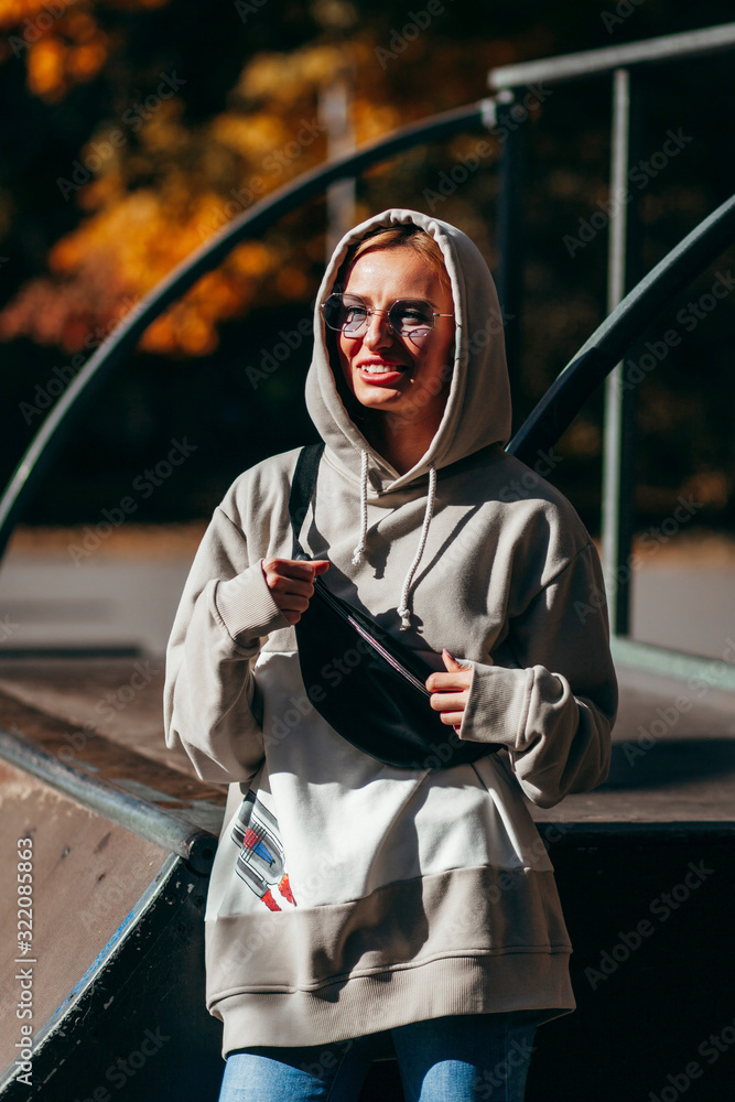 Sticker stylish model girl at skate park in glasses with waist bag