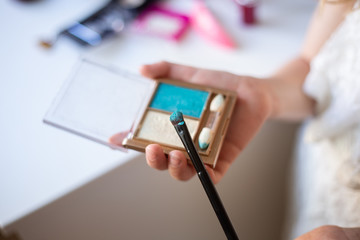 charming child, little beauty, cute girl of 7-8 years old with beautiful blond curls, make-up, mom’s makeup at the table, gray background