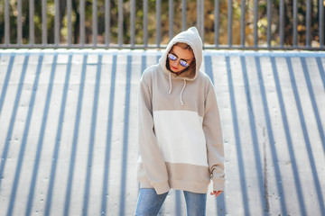 Outdoor photo of pretty, young model girl dressed in gray hoodie