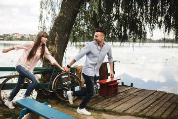 Obraz premium Happy young couple outdoors. young love couple running along a wooden bridge holding hands.