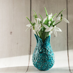 Bouquet of the first spring flowers snowdrops in the vase. Background with copy space