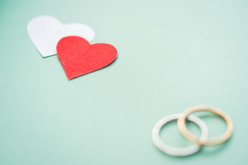 Wedding Rings Background. Valentine's day - Wedding rings blurred with selective focused red heart on light cyan pastel color background with copy space. Concept for couple love, wedding card.