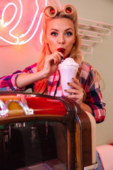 Fototapeta na wymiar Photo of young pleased woman drinking milkshake while leaning jukebox