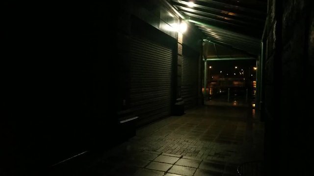 Dark alley shopping store front shutters on cold stormy windy night.