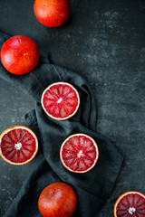 Flat lay food composition with blood oranges on a dark blue background.