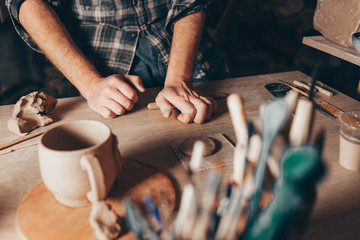 Male potter rolls clay to create a cup
