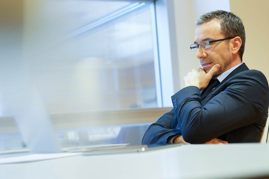 Businessman at work being thoughtful in front of laptop