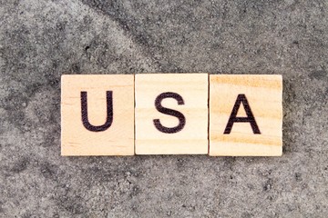 USA word written on wood block, on gray concrete background. Top view. United States of America