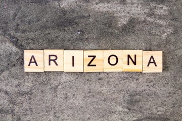 Arizona word written on wood block, on gray concrete background. Top view.