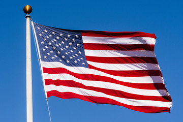Beautifully waving star and striped American flag on a blue sky background; Close Up for Memorial Day or 4th of July