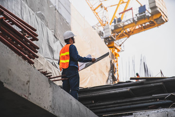 Engineer in hardhat and orange jacket posing on building site. civil engineer or architect with...