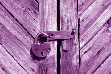 Grungy wooden door with lock in purple tone.