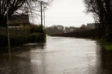 Image in Thornton England of Stannah Road flooded to the curb and over with water due to Storm Ciara not allowing anyone to pass and cars becoming stuck in the flood disrupting travel plans