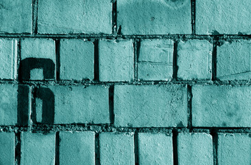 Number 6 in stencil on rusty brick wall in cyan tone.