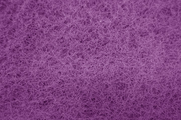 Cleaning sponge rubbing surface close up with blur effect in purple tone.