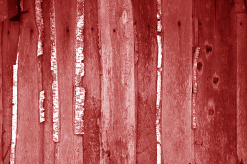 Wall made of uncutted weathered wood boards in red tone.