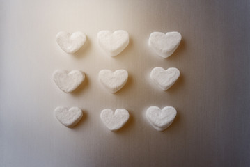 white marshmallows in the shape of sugar hearts on a dark gray aluminum background
