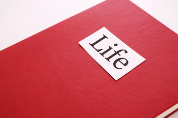 on the red book is pasted a strip of paper on which is written life