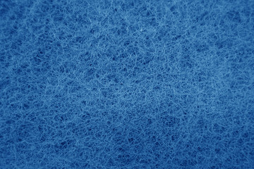 Cleaning sponge rubbing surface close up with blue effect in navy blue tone.