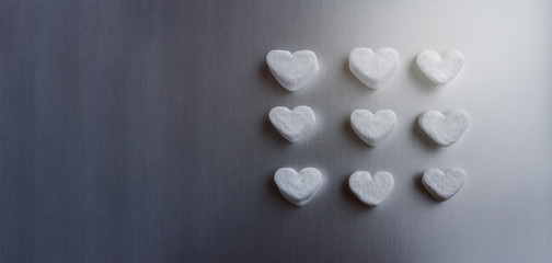 white marshmallows in the shape of sugar hearts on a dark gray aluminum background