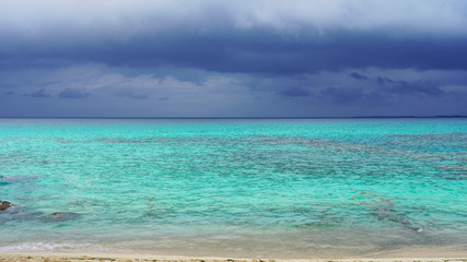 Obraz premium Incredible bright blue turquoise water of the Pacific Ocean off the coast of a tropical island. stormy sky over bright clear sea water