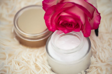 Fototapeta na wymiar Skincare concept. cream in a glass jar with an open lid and a rose