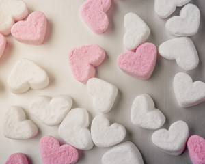 pink and white heart-shaped marshmallows evenly laid out on gray aluminum background