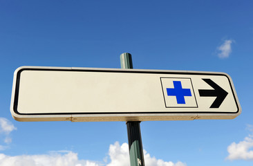 Information sign of a hospital with blue cross and direction arrow