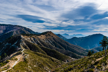 Fototapeta na wymiar Beautiful captivating landscape of the layered French Alps mountain range in Alpes-Maritimes in the afternoon during a sunny day with a hiking path trail