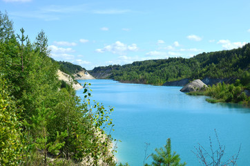 Fototapeta na wymiar Chalk quarry artifical lakes in Belarus at Krasnoselsky village. Turquoise background of the clear ocean water in summer tropical season. Technogenic open pit for tourism