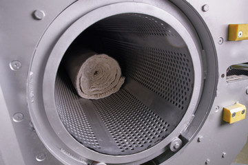 Men workers get carpet from an automatic washing machine and put in in dryer in the Laundry service
